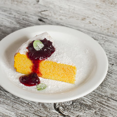 Cottage cheese and pumpkin casserole with  berry sauce on a white plate on a light wooden board