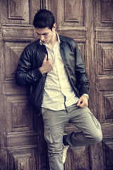 Obraz premium Handsome young man in front of wood door