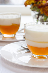 Vanilla and orange Panna Cotta in the cup on white saucer