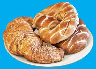 Plate of Pretzels and Croissant Puff Pastry Sprinkled with Sesame Seeds, Isolated on Blue Background.