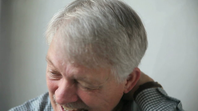 A senior man massages his painful neck.