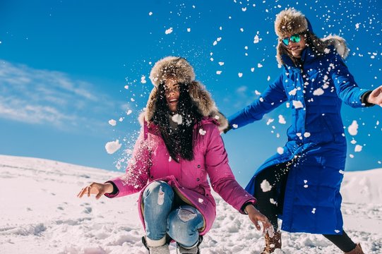winter, two cheerful young girls having fun in the snow in the m