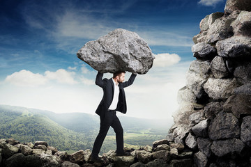 man in formal wear holding big stone and walking