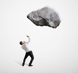 scared businessman under big flying stone