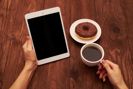 Womans Hands Holding Tablet Pc And Cup Of Coffee Over Brown Back