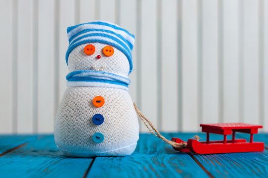Funny snowman with red sleg or sleigh on wooden background. Xmas Background