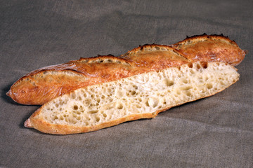 cut across the long white bread lies on a grey linen tablecloth