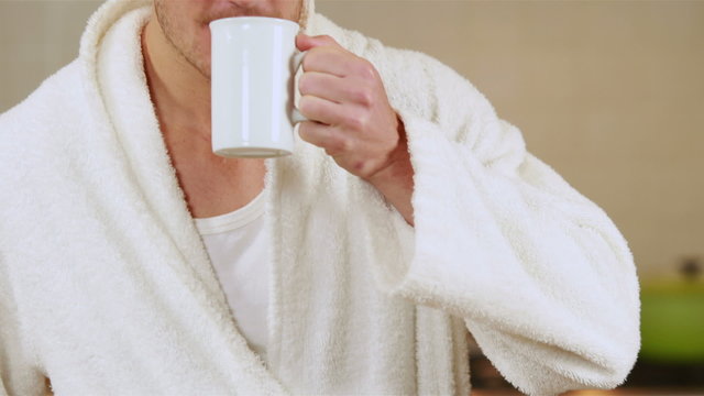 Handsome man drinking coffee in bath robe
