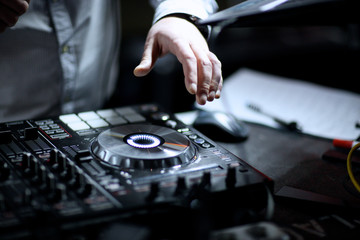 Hands of a D.J. mixing recorded music at event