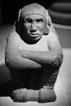 Closeup of an old stone sculpture of an aborige sitting