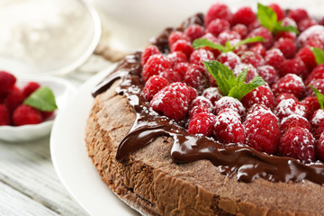 Cake with Chocolate Glaze and raspberries and cup of tea on color wooden background