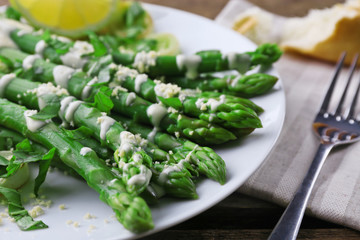 Served wooden table with asparagus dish and wine, close up