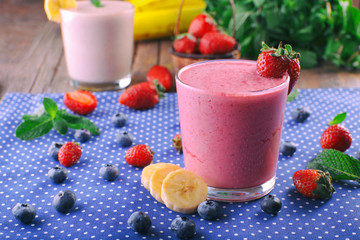 Glasses of fresh cold smoothie with fruit and berries, on blue tablecloth background