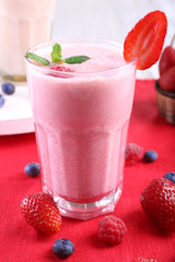 Milkshakes with berries at red textile on light background