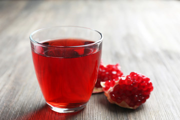 A glass of tasty juice and garnet fruit, on wooden background