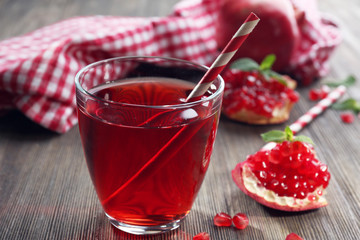 A glass of tasty juice and garnet fruit, on wooden background, close-up