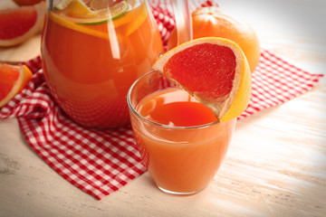 Jar of citrus juice and fresh fruits on light wooden background