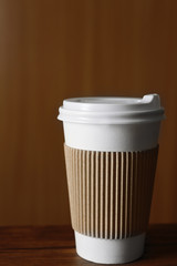 Paper cup of coffee on table, on wooden background