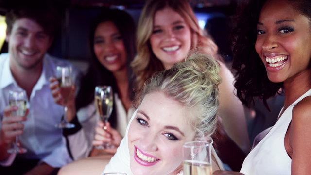 Happy friends drinking champagne in limousine