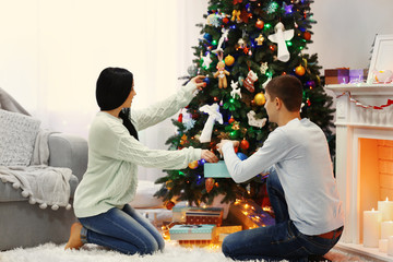 Happy couple on the floor with gifts in the decorated Christmas room