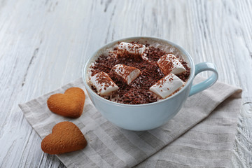 Cup of hot cacao with marshmallow and heart shaped cookies on cotton serviette, close up