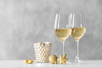 Two glasses of wine with Christmas toys on grey wall background