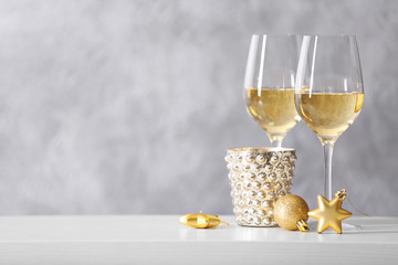 Two glasses of wine with Christmas toys on grey wall background
