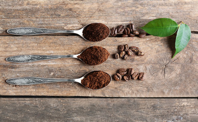 Spoons with coffee on wooden table, close up