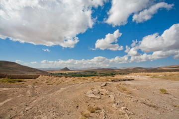 Beautiful valley in the Middle East with low mountains and small town in the distance under clouds
