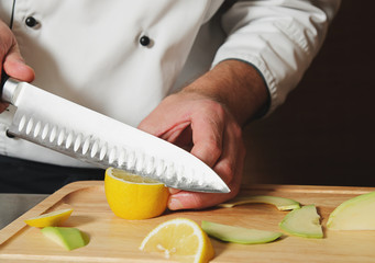 chef cutting lemon on table
