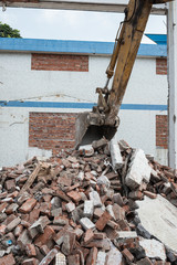 excavator demolishing concrete and brick rubble debris vertical