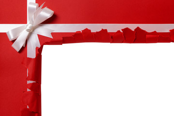Christmas gift torn open white ribbon bow red wrapping paper background opening unwrapping present...