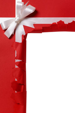 Christmas gift torn open white ribbon bow red wrapping paper background opening unwrapping present photo vertical