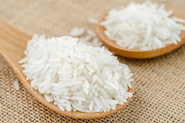 Raw rice in wooden spoon.
