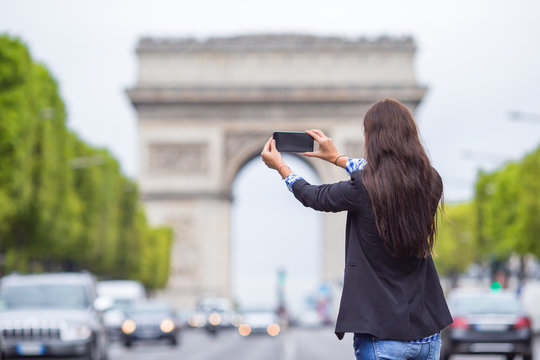 Young woman taking a photo with her phone on the Champs Elysees in Paris