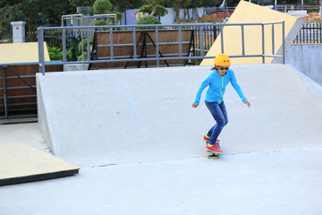 skateboarding young woman riding on a skateboard at skatepark