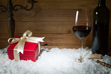 Concept of celebration with gift box, wine glass on snow and woo