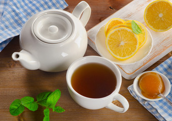 Teapot and cup with tea with lemon and mint