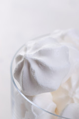 Closeup of meringue cookies in a glass on a white background