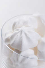 Closeup of meringue cookies in a glass on a white background