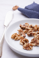 Walnuts on a white ceramic plate with blue napkin and knife..