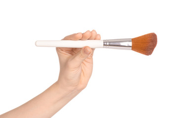 Makeup and beauty topic: a woman's hand holding a brush makeup isolated on white background in studio