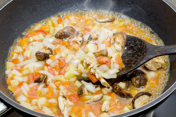 cooking pasta with chicken and meat gravy on stove