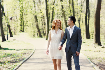 happy wedding couple, elegant bride and handsome groom walking in sunlit park