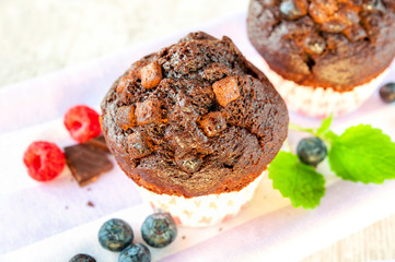 Two delicious chocolate muffins with pieces of chocolate and ber