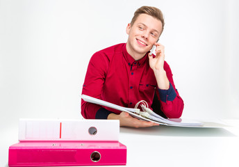 Playful cheerful young man using binders and talking on cellphone