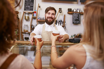 Friendly man serving coffee for two women