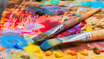 Fototapeta premium Used brushes on an artist's palette of colorful oil paint