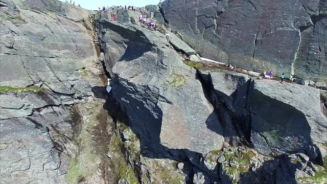 Aerial footage of Trolltunga rock in Norway, famous tourist destination with crowds of tourists waiting to take a photo on the rock. Aerial 4k Ultra HD.