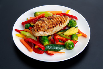 Grilled chicken fillet, breast with cooked vegetable  on plates.